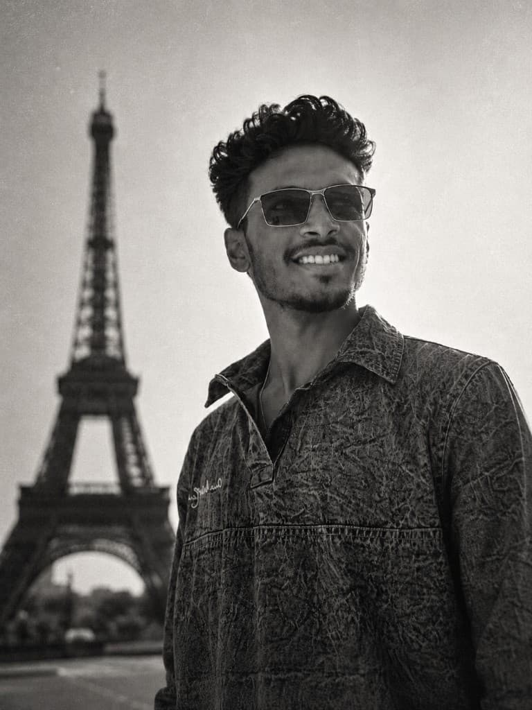 Aravind Sriram smiling in front of the Eiffel Tower